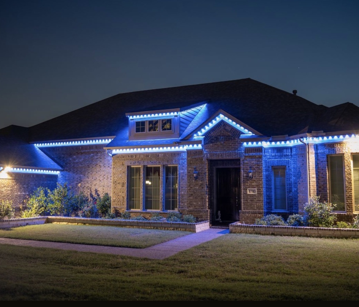 Blue and white lights highlighting a single-story brick home's roofline