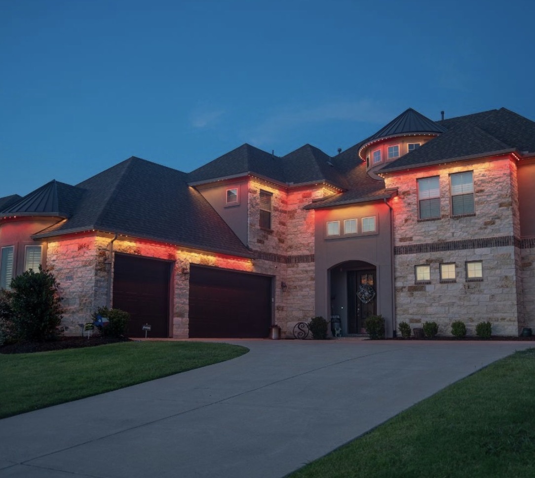 Warm amber and red exterior lights highlighting a stone home's architecture
